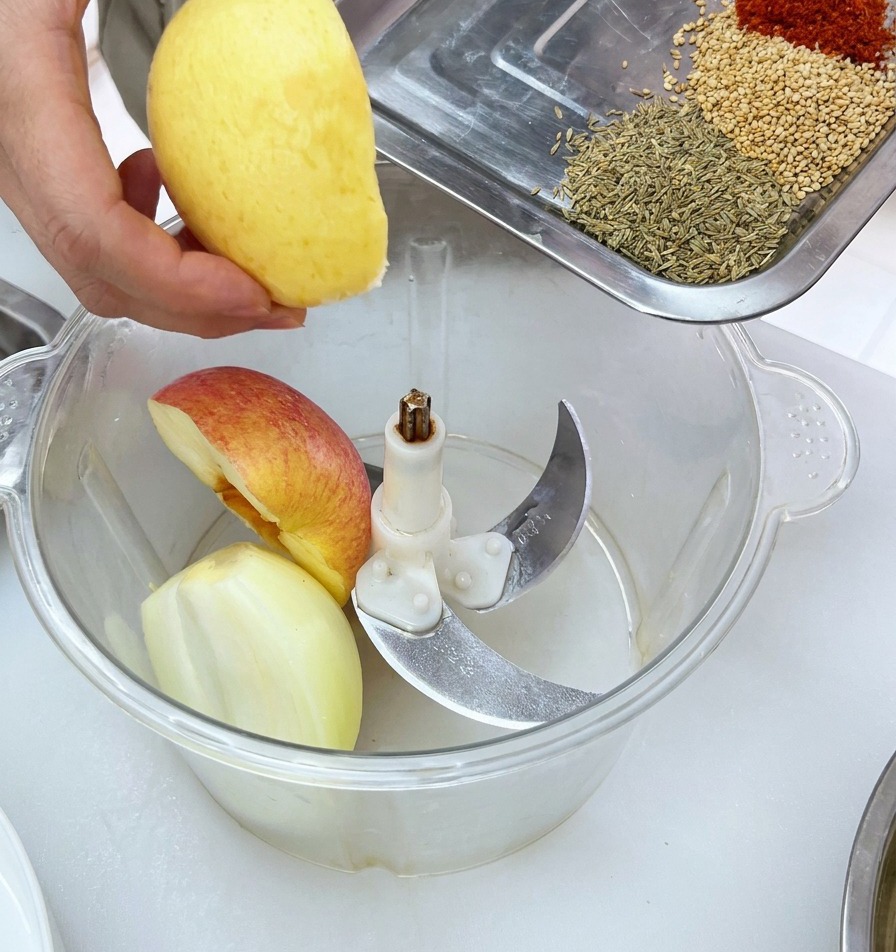 Morceaux de fruits frais déposés dans le bol dun robot culinaire, avec un plateau dépices prêt à être incorporé.