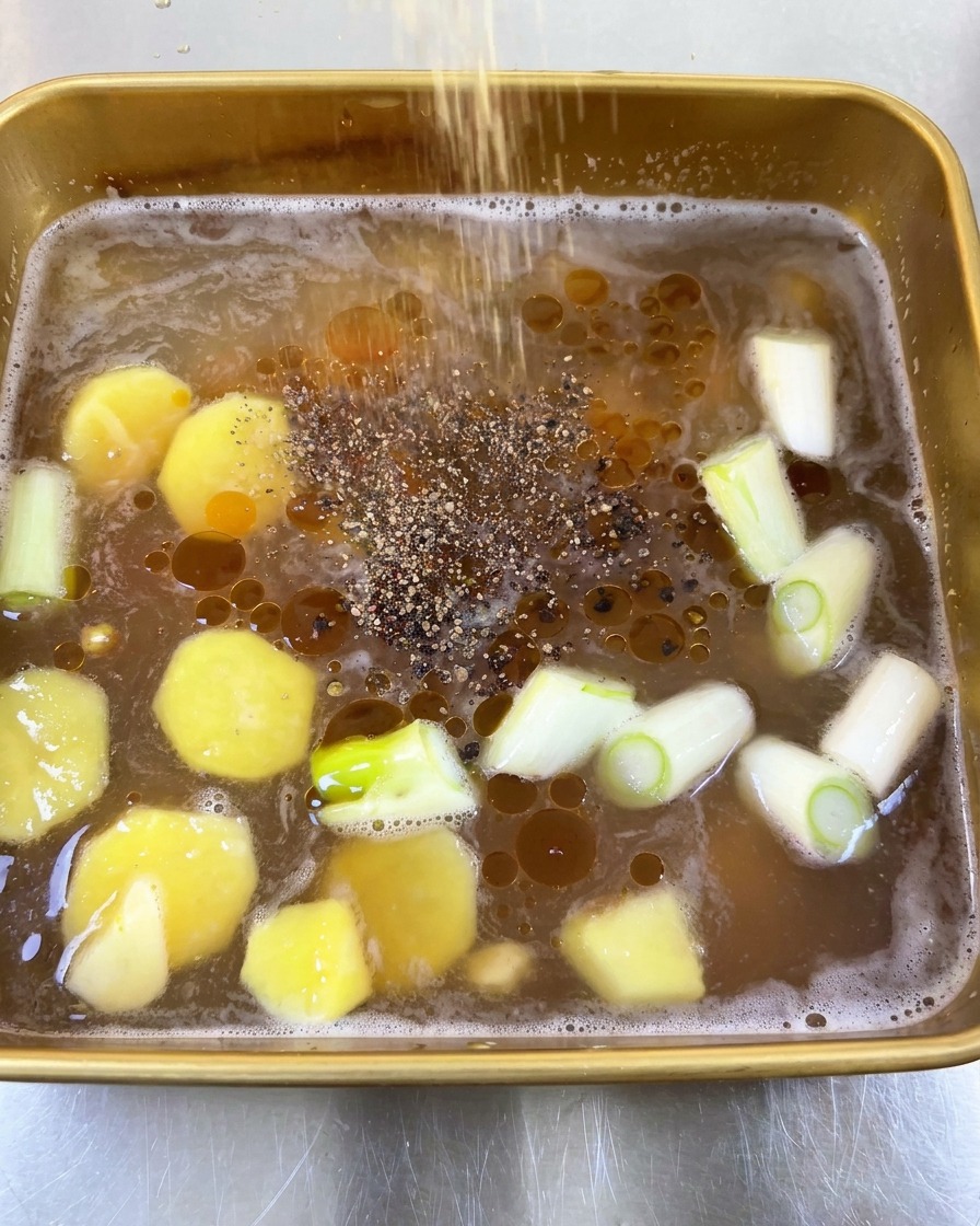 Du poivre noir moulu saupoudré généreusement sur la marinade liquide huileuse.