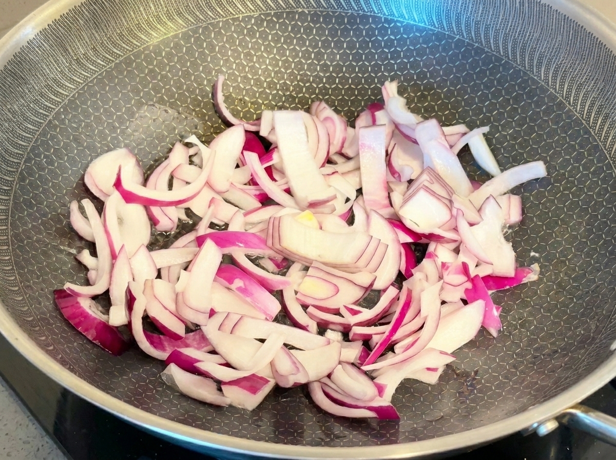 Lamelles doignon rouge éclatantes sautées dans une poêle métallique texturée.