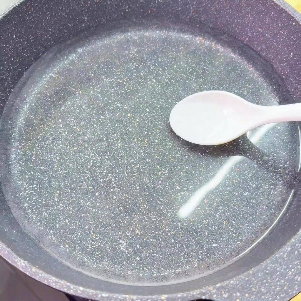 Une cuillère blanche dépose du sel dans un wok rempli deau claire et froide.