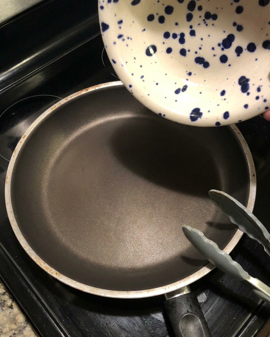 Marinade sombre versée depuis un bol en céramique dans une poêle chaude pour créer une réduction de sauce.