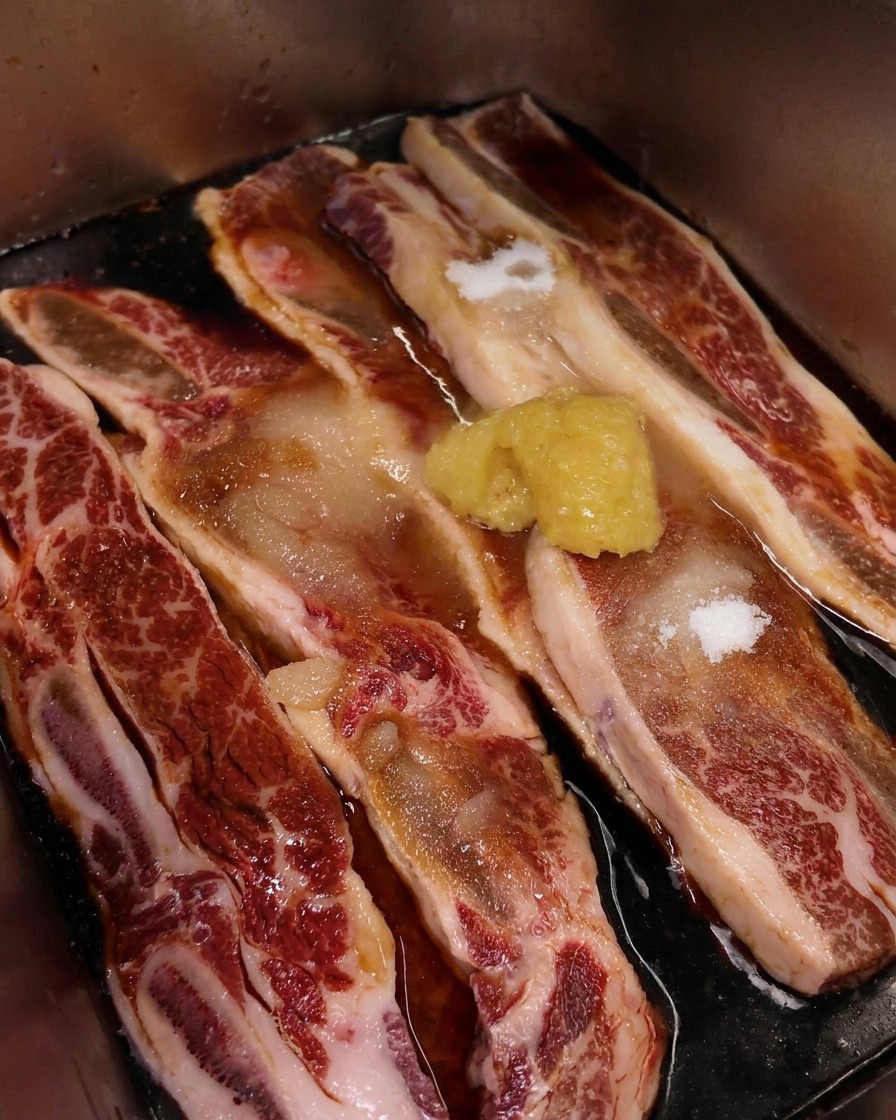 Gros plan sur un monticule dail haché déposé sur la viande de bœuf marbrée en cours de marinade.