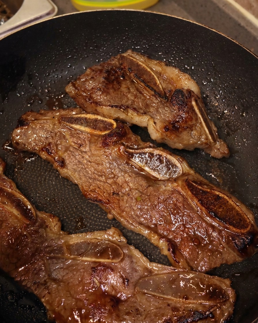 Ciseaux de cuisine découpant le bœuf entre les os directement dans la poêle.