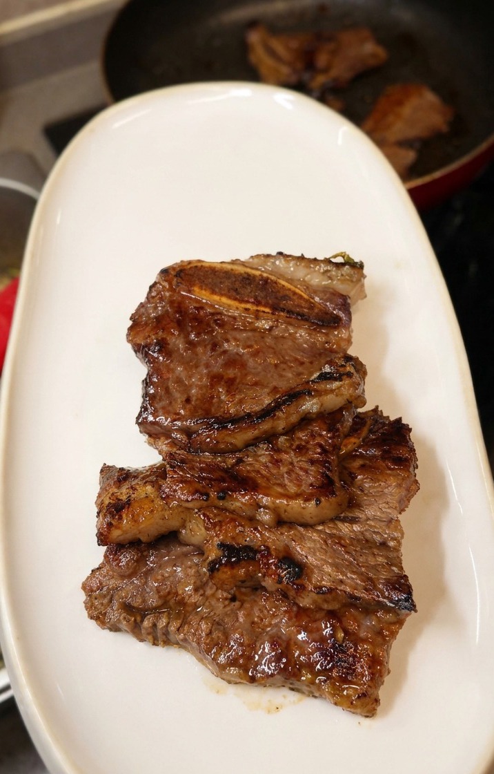 Pile de travers de bœuf LA Galbi bruns et juteux servis sur une assiette ovale blanche.