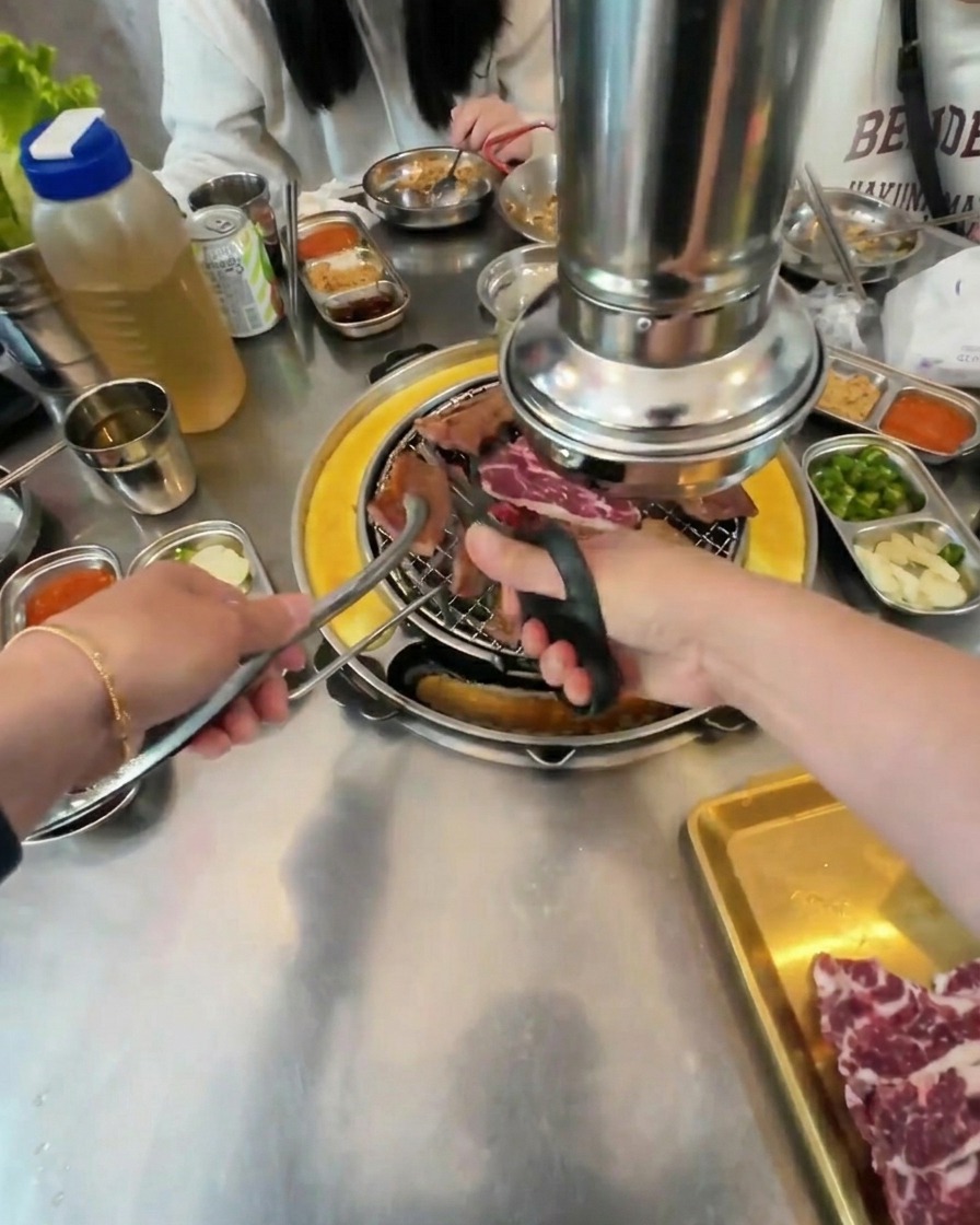 Gros plan de ciseaux découpant le bœuf grillé en petits carrés au-dessus du charbon chaud.