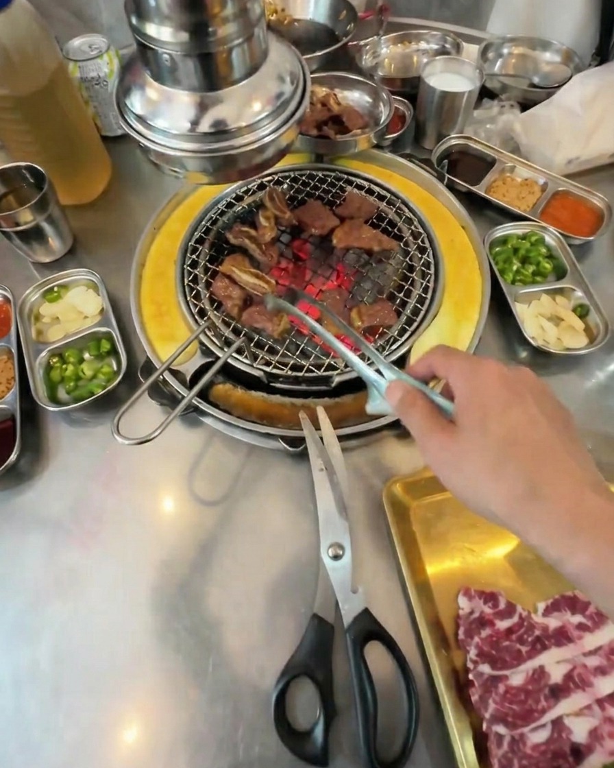 Petits cubes de bœuf grillés remués avec une pince sur la grille du barbecue.