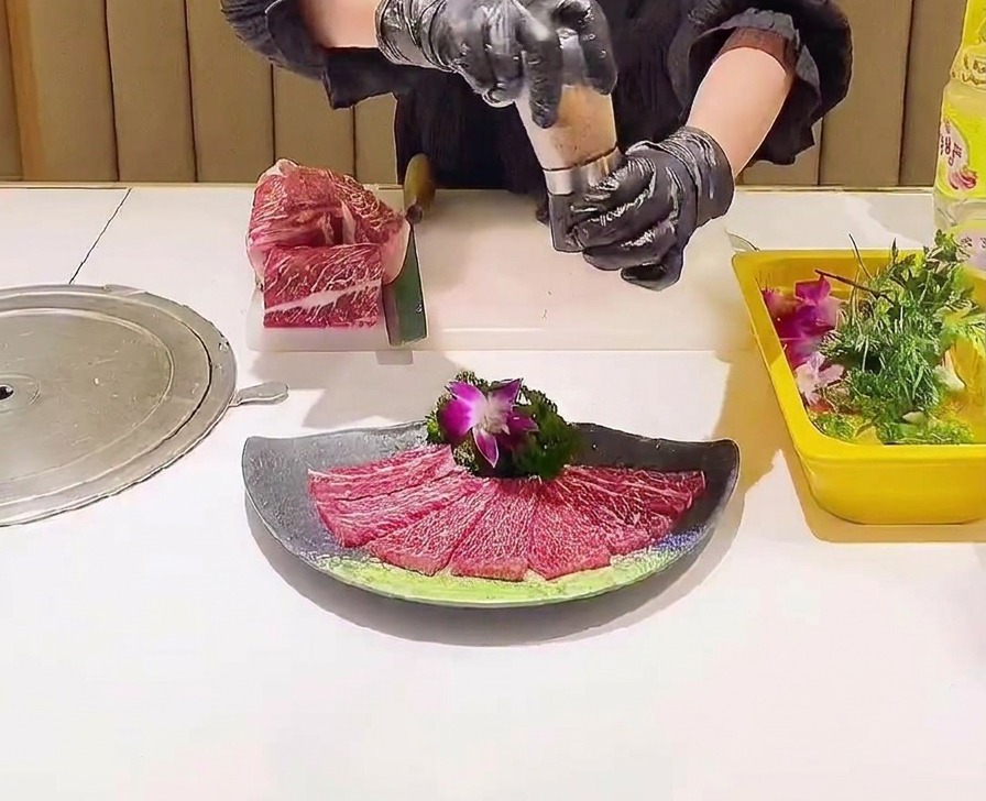 Un moulin à sel saupoudrant des cristaux de sel rose sur un agencement décoratif de tranches de bœuf crues.
