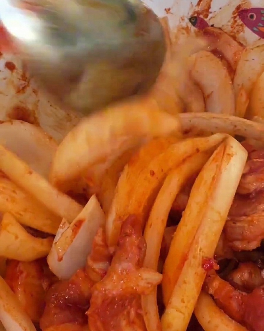 Larges tranches doignons blancs incorporées au porc mariné rouge vif dans un bol.