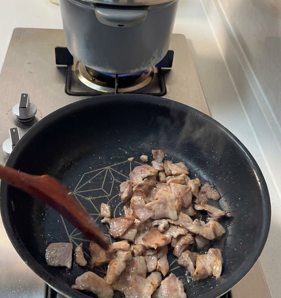 Morceaux de porc dorés et croustillants sur les bords sautés dans une poêle sombre.