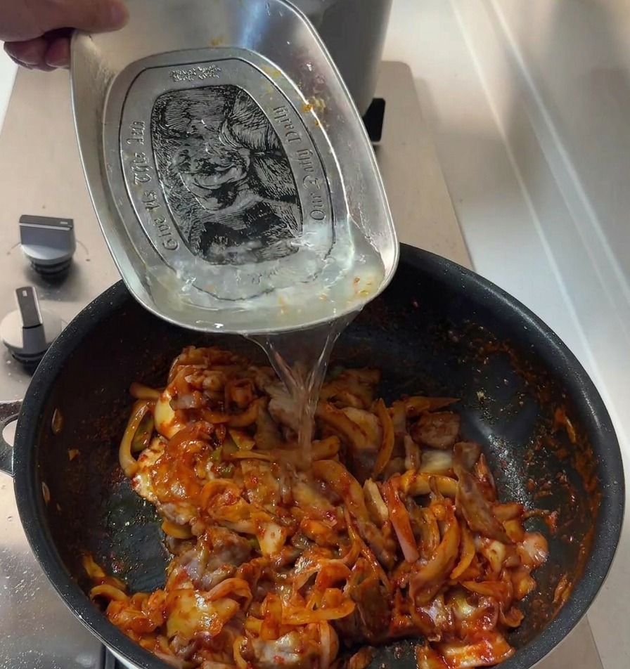 Un peu deau ajoutée à la poêle de porc épicé au kimchi pour lier la sauce.