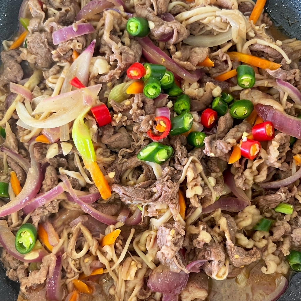 Piments rouges et verts tranchés posés sur le bulgogi de bœuf cuit dans la poêle.