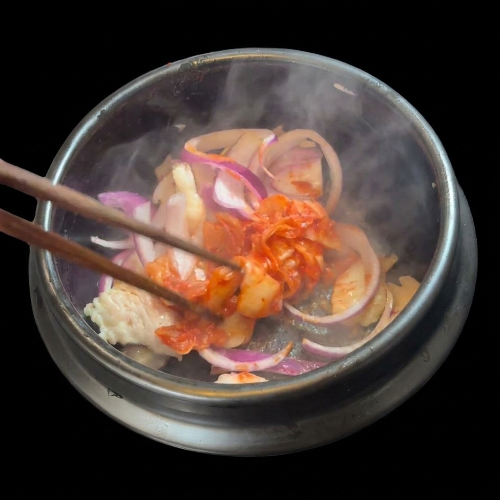 Une poignée de kimchi rouge haché ajoutée au mélange de porc et doignons dans le pot.