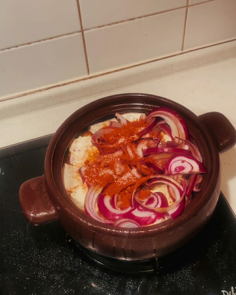 Main saupoudrant du sucre blanc sur les oignons et le piment dans le pot.