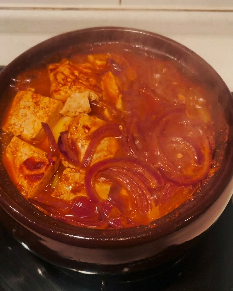 Le ragoût de kimchi rouge bouillonnant activement dans son pot sur le feu.