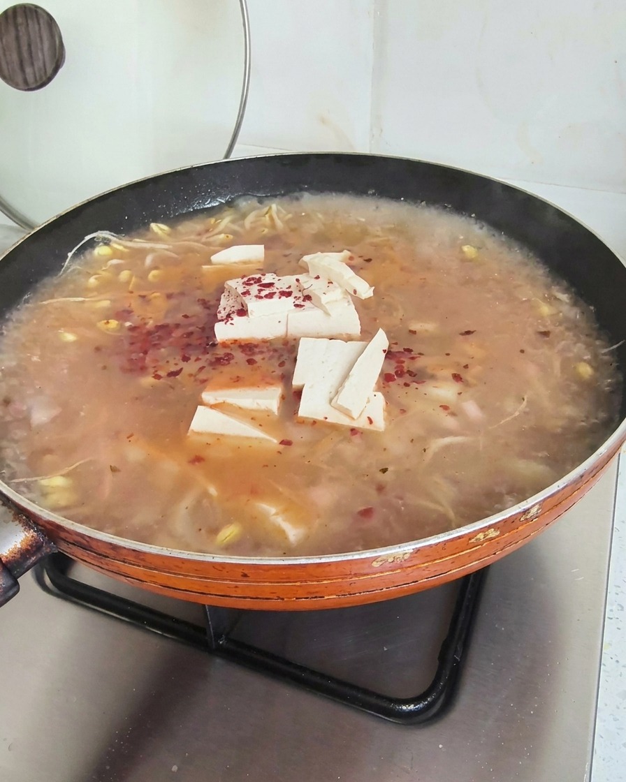 Flocons de piment rouge vif dispersés sur une soupe fumante avec tofu et pousses de soja.