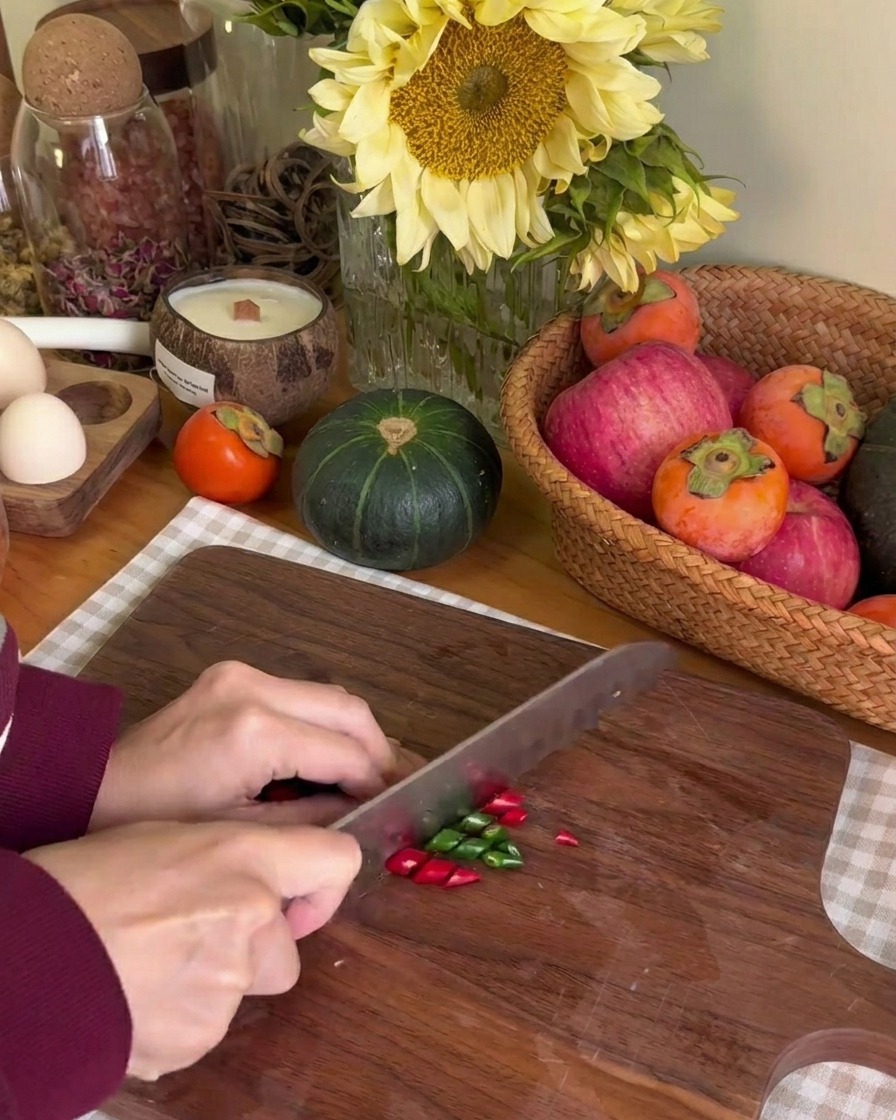 Découpe de petits piments rouges et verts en fines rondelles sur une planche en bois