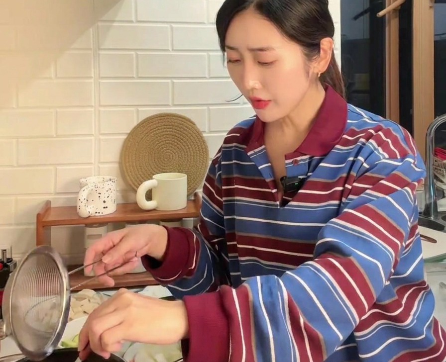 Pâte de soja brune tamisée à travers une passoire dans une casserole deau bouillante à laide dune cuillère