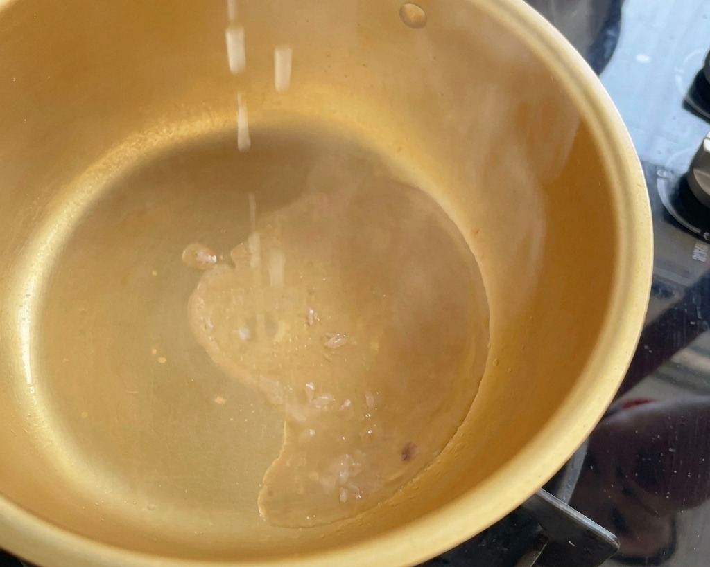 Oignons verts hachés tombant dans une marmite fumante contenant lhuile de thon chaude.