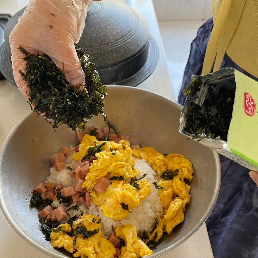 Gros morceaux de thon en conserve ajoutés dans un ragoût de kimchi rouge bouillonnant.