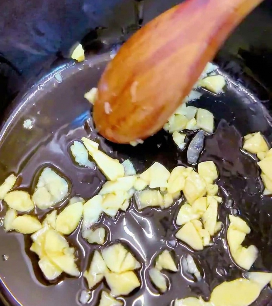 Morceaux de kimchi rouge épicé ajoutés dans la marmite avec lail.