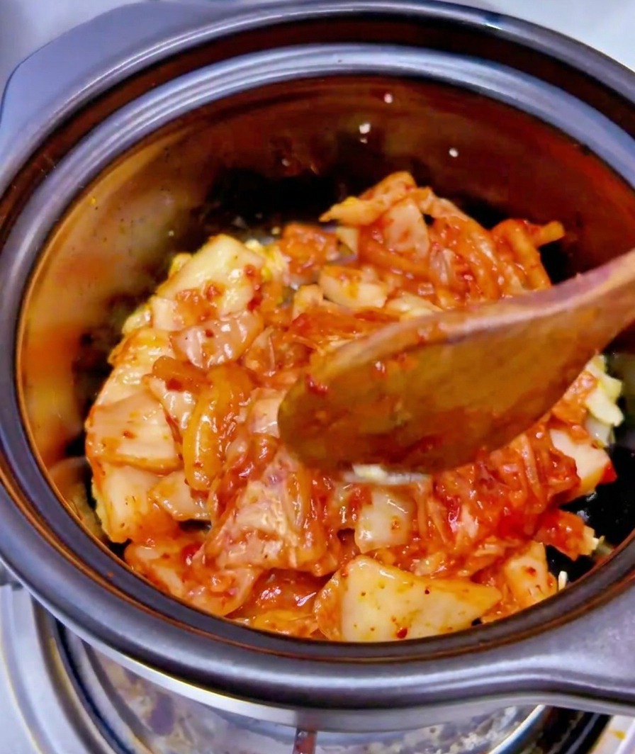 Le liquide dune boîte de thon versé sur le mélange de kimchi et dail.