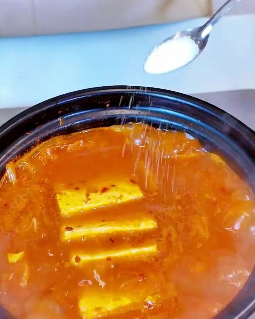 Sel blanc saupoudré à la cuillère sur la surface de la soupe frémissante.