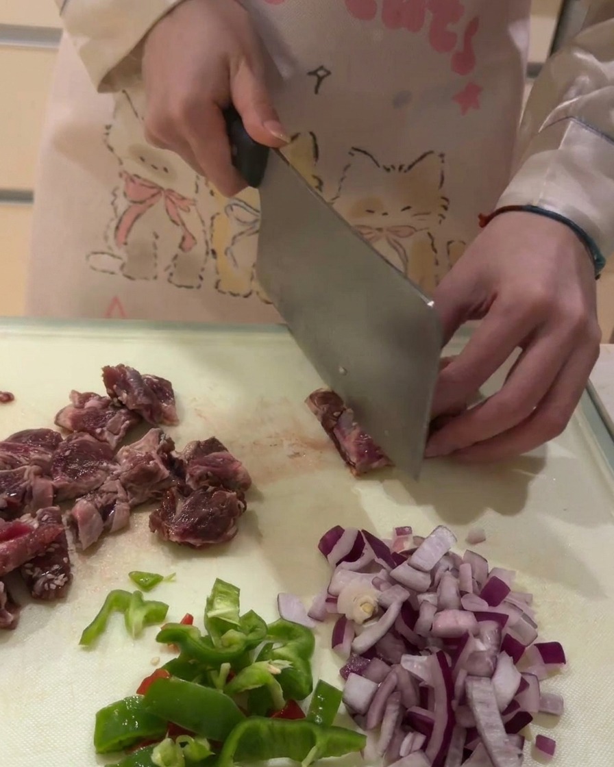 Gros plan sur la découpe de travers de bœuf crus en petits cubes sur une planche à découper blanche.