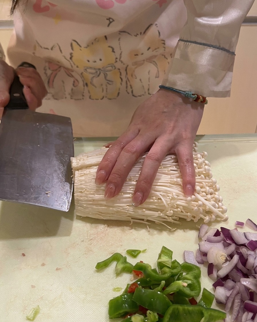 Découpe de la base dun bouquet de champignons enoki blancs sur un plan de travail.