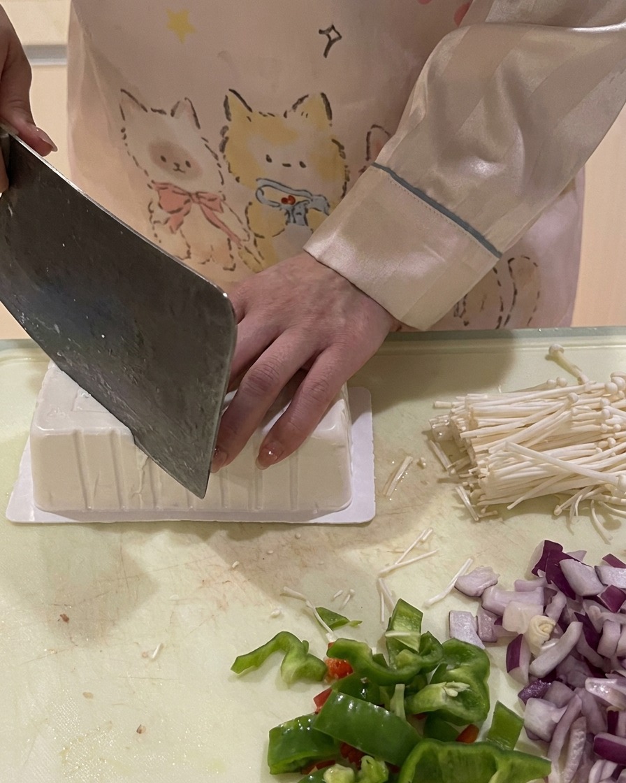 Couteau coupant le coin dun paquet de tofu inversé pour laisser entrer lair et faciliter le démoulage.