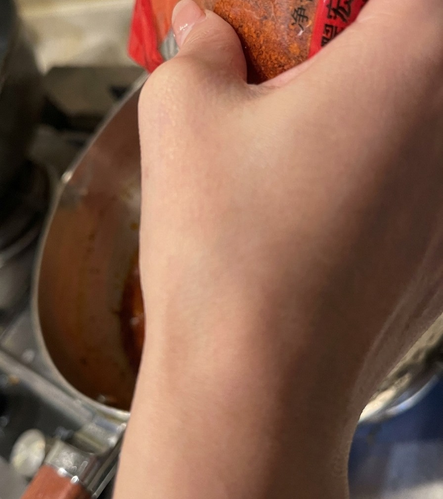 Poudre de piment rouge saupoudrée dans le bouillon orange frémissant.