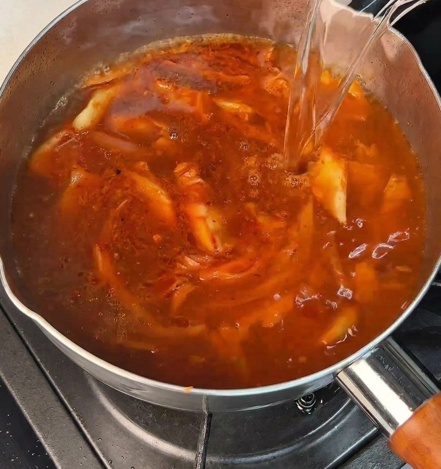 De leau bouillante versée dans une marmite avec une base rouge bouillonnante.