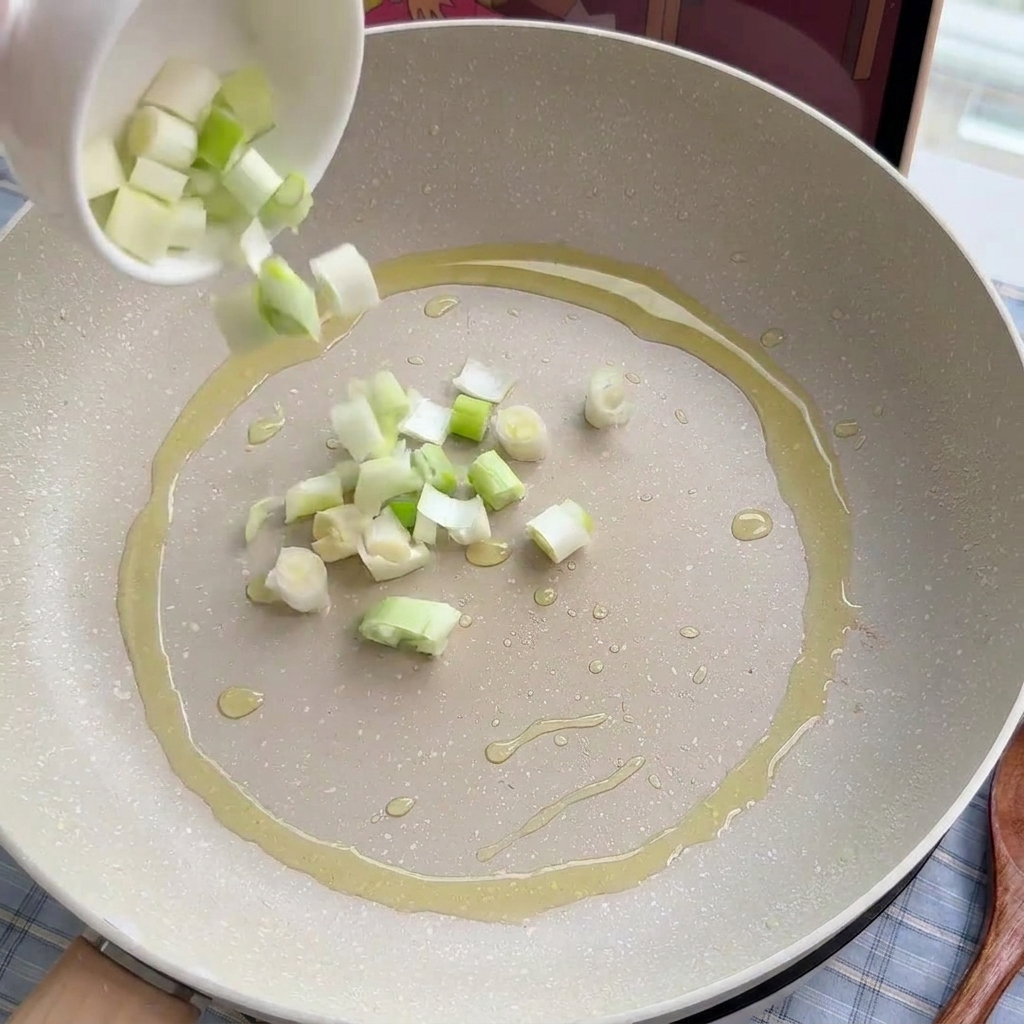 Oignons verts et poireaux émincés sautant doucement dans un peu dhuile.