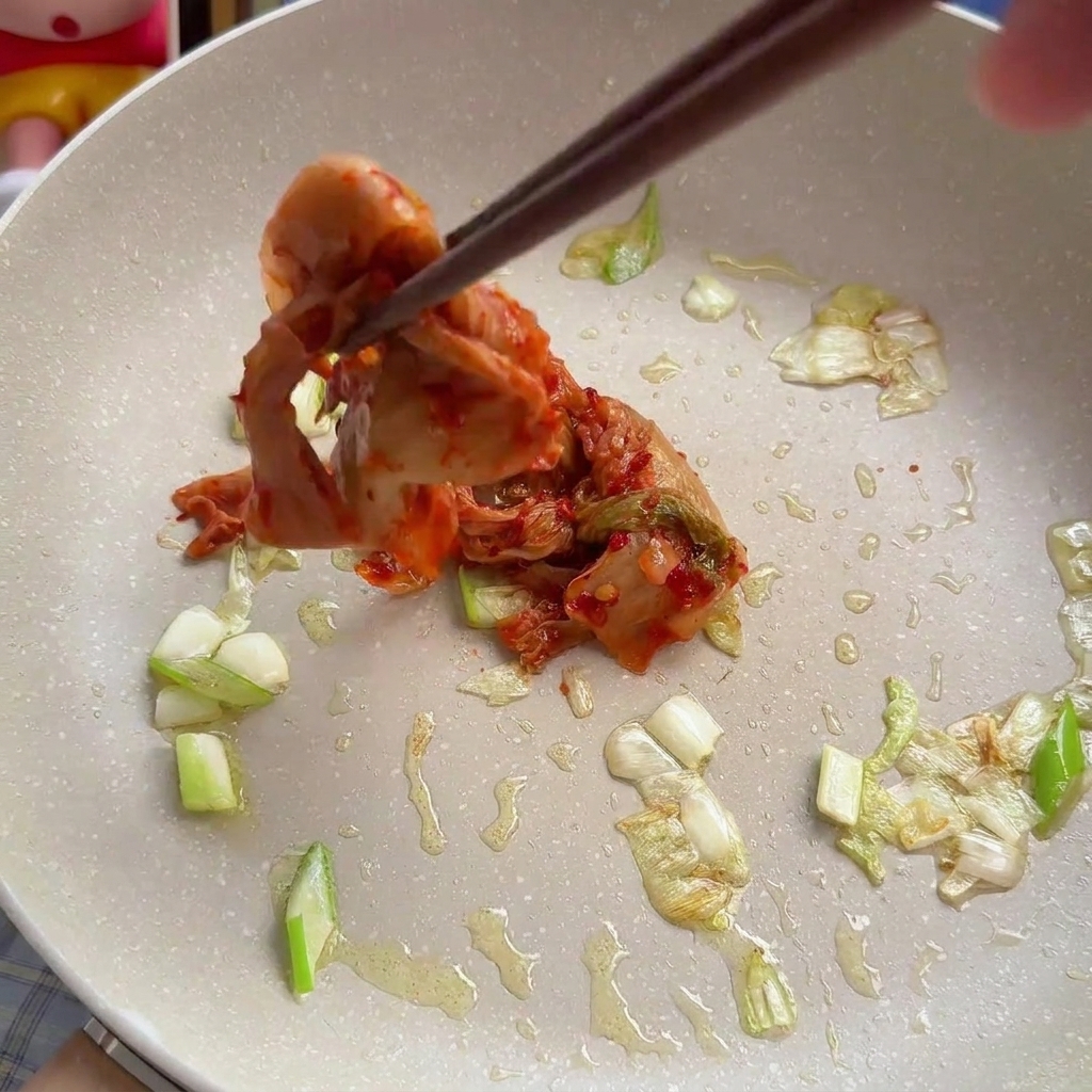 Ajout de kimchi de chou émincé aux oignons verts dans le faitout.