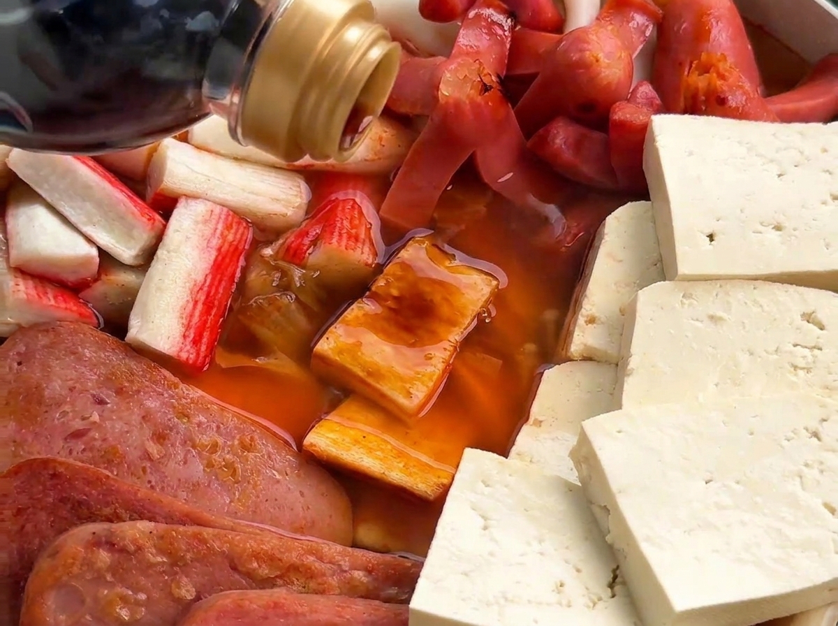 Versement de sauce soja foncée dans le bouillon bouillonnant.