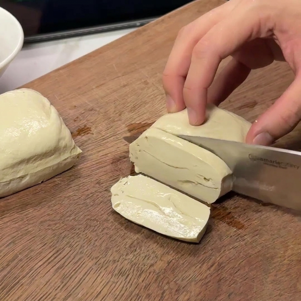 Découpe dun bloc de tofu blanc ferme en morceaux rectangulaires réguliers.