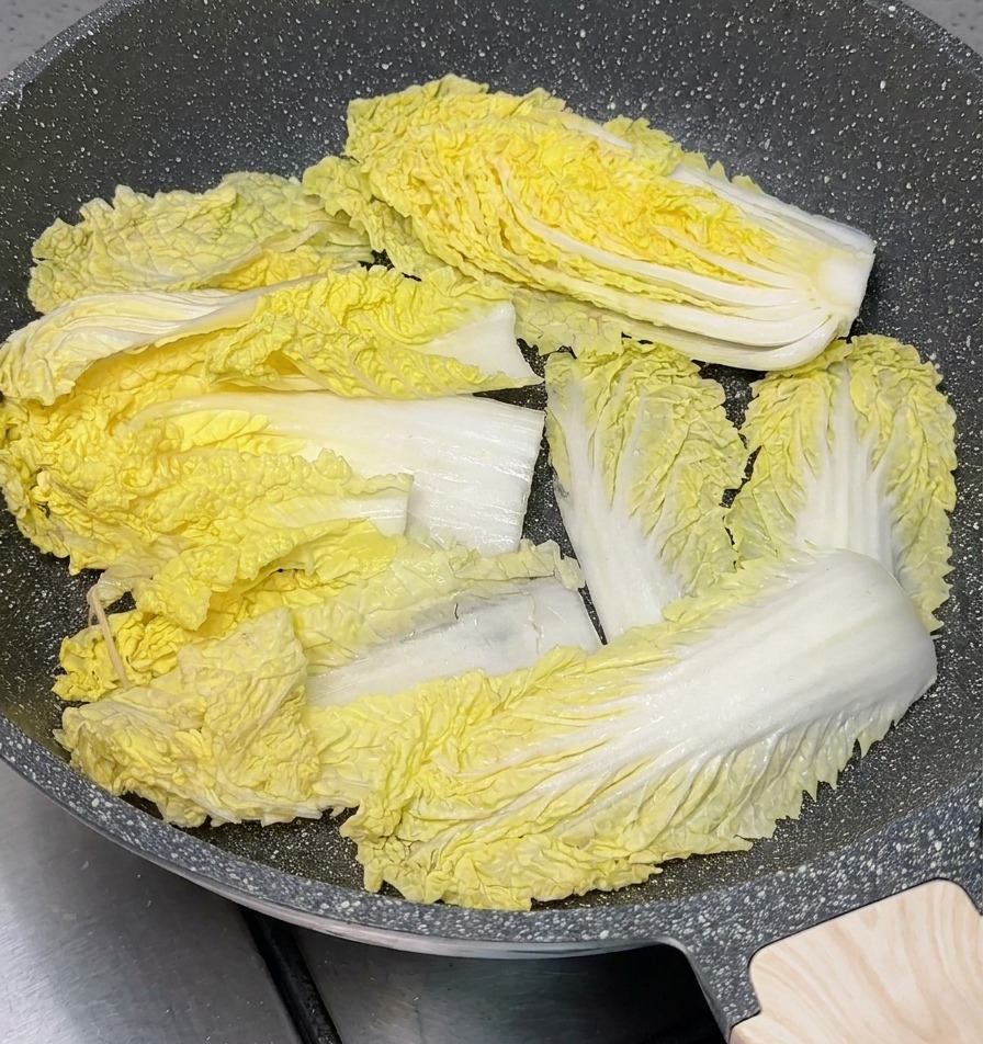Sections de chou chinois disposées au fond dune marmite de cuisson grise.
