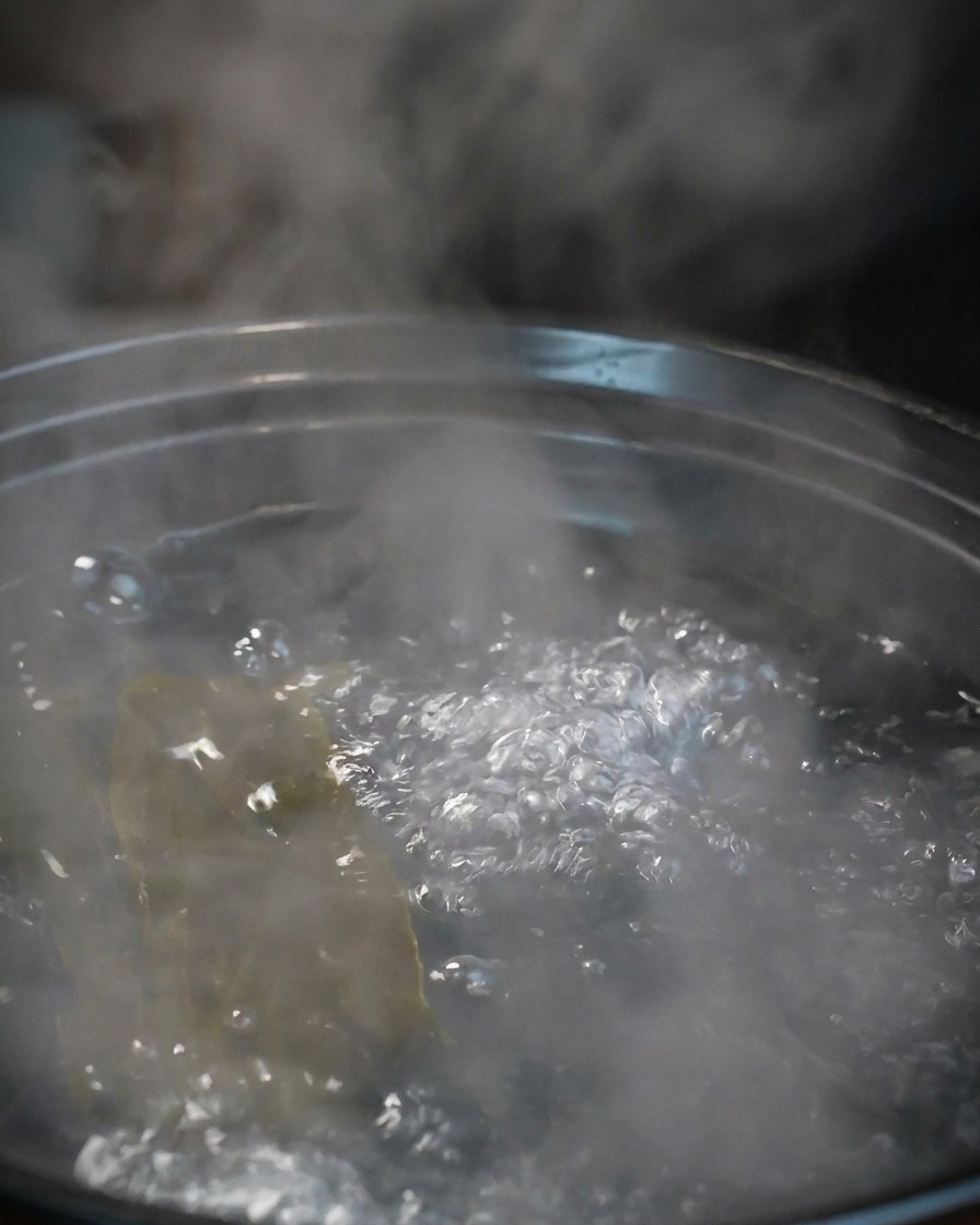 Plusieurs grosses crevettes grises crues ajoutées au bouillon de kombu bouillant.