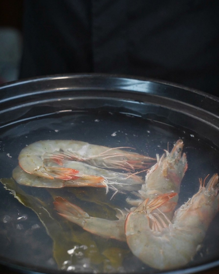 Palourdes fraîches versées dans la casserole contenant déjà les crevettes et le bouillon.