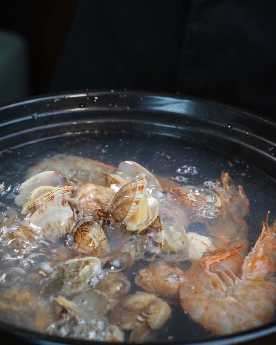 Morceaux de tentacules de poulpe crus ajoutés à la marmite de soupe de fruits de mer.