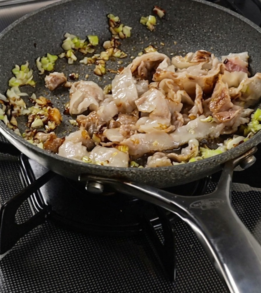 Lamelles de porc et légumes sautés dans une poêle jusquà ce que la viande soit dorée.