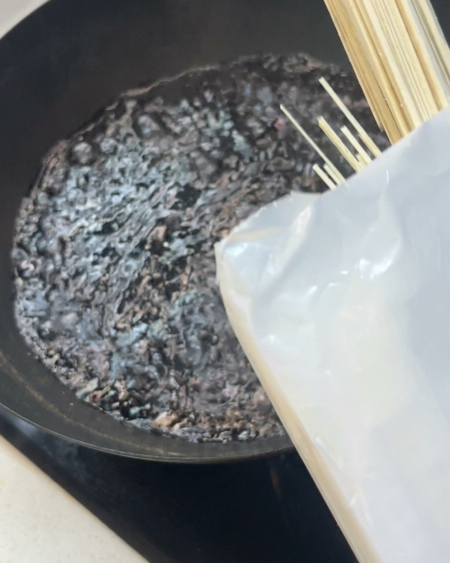 Un faisceau de nouilles blanches sèches placé dans un wok deau bouillante.