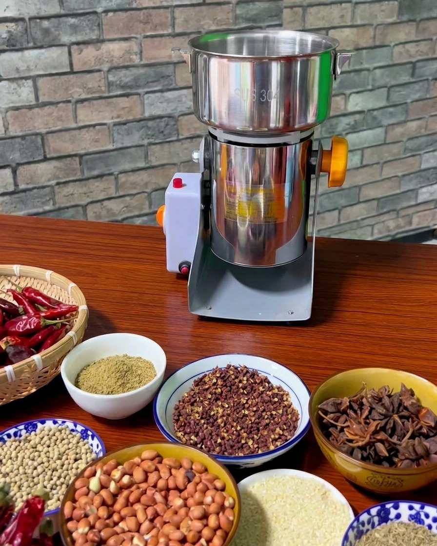 Assortiment de bols contenant les épices torréfiées sur une table en bois à côté dun moulin à épices électrique.