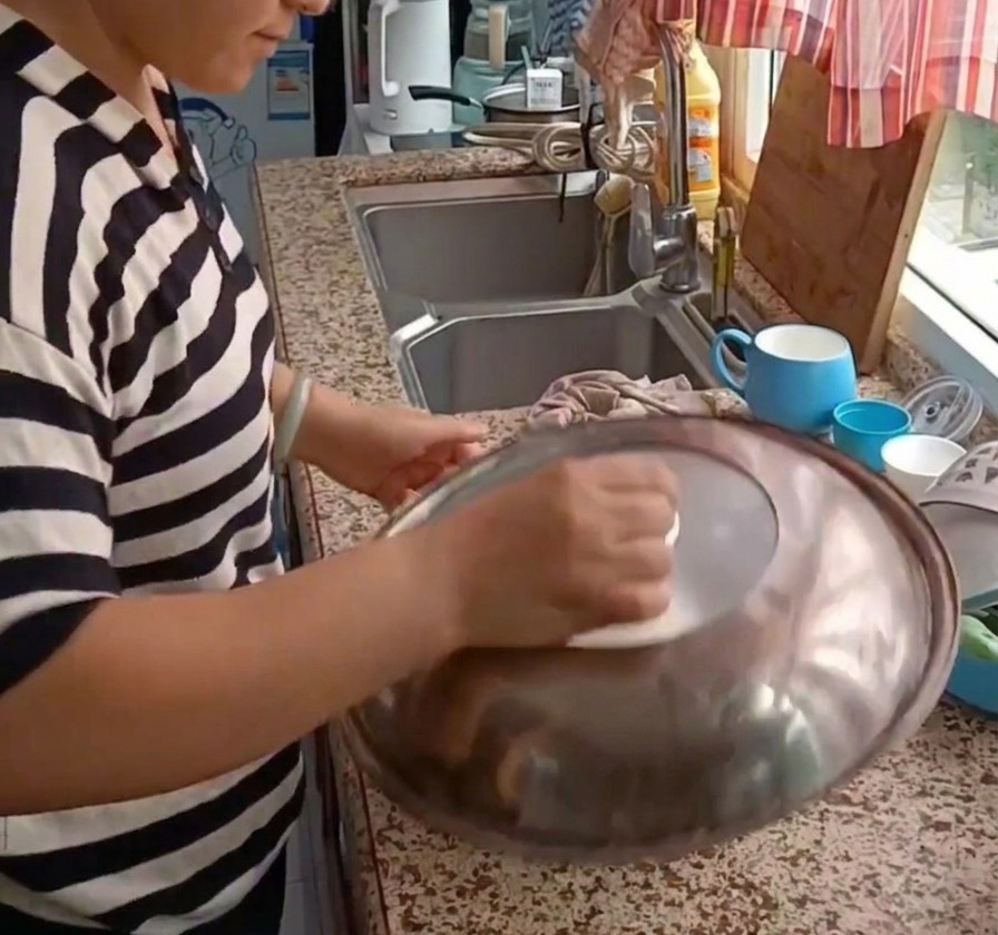 Une personne plaçant un grand couvercle métallique sur un bol contenant de la pâte pour la laisser reposer.