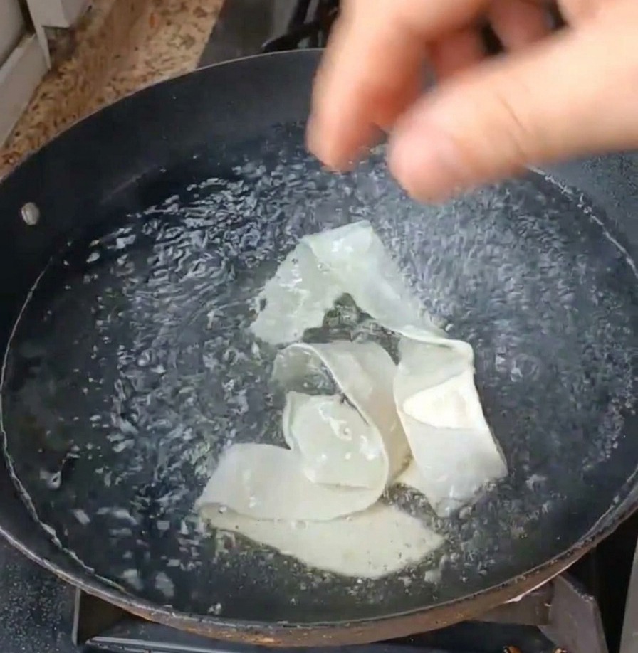 De larges rubans de nouilles et des légumes verts plongés dans une casserole deau bouillante.