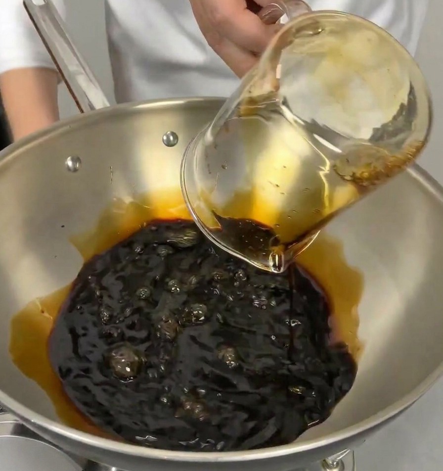 Verre doseur versant du mirin ou du saké transparent dans la casserole contenant déjà la sauce soja.