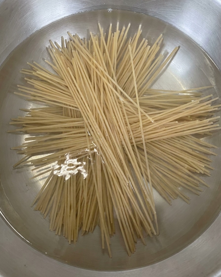 Nouilles de sarrasin sèches plongées en éventail dans une casserole deau bouillante.