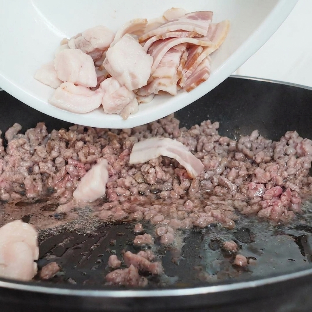 Tranches de champignons versées depuis une assiette sur le bœuf haché en cours de cuisson.
