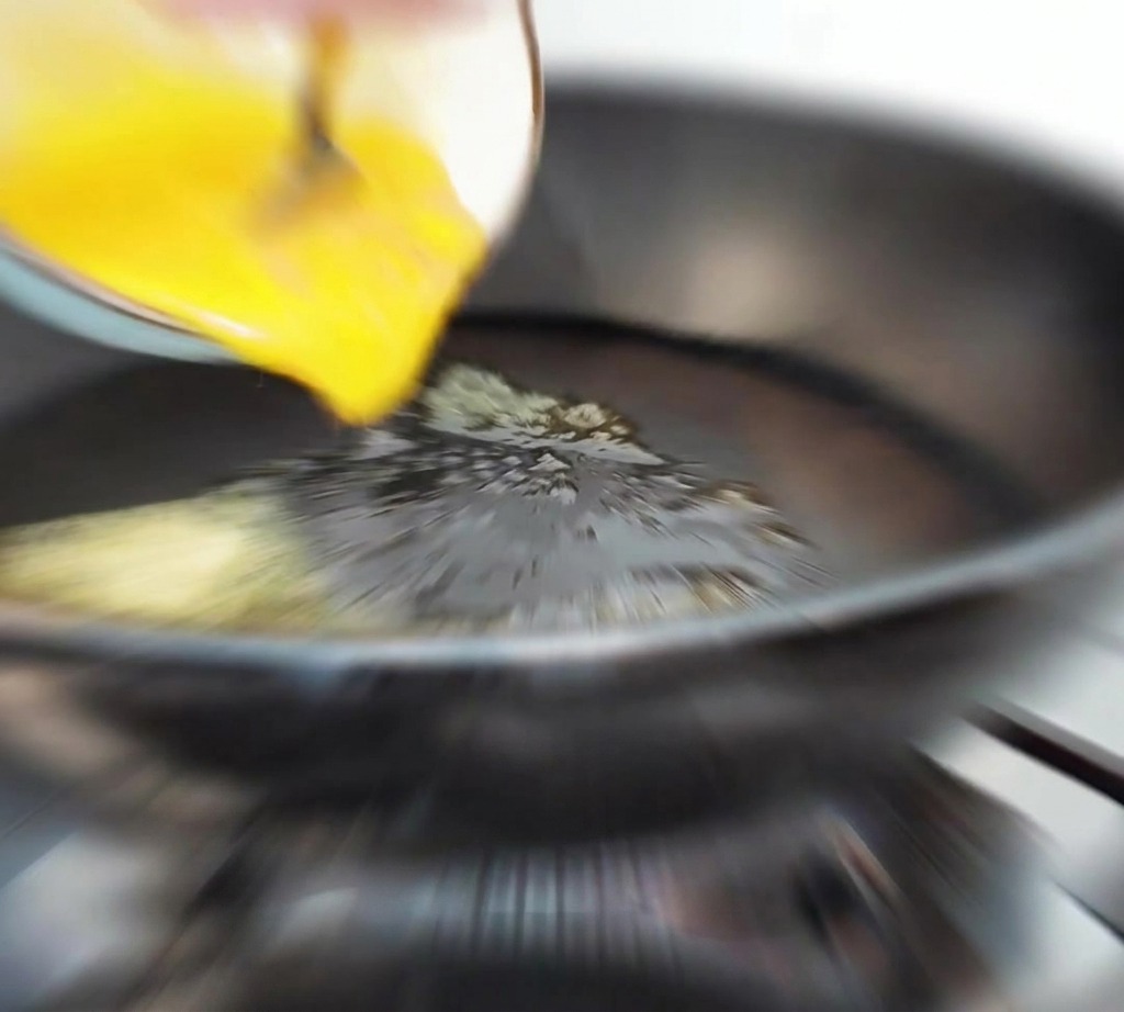 Œufs battus versés dun bol dans une poêle chaude avec du beurre fondu.