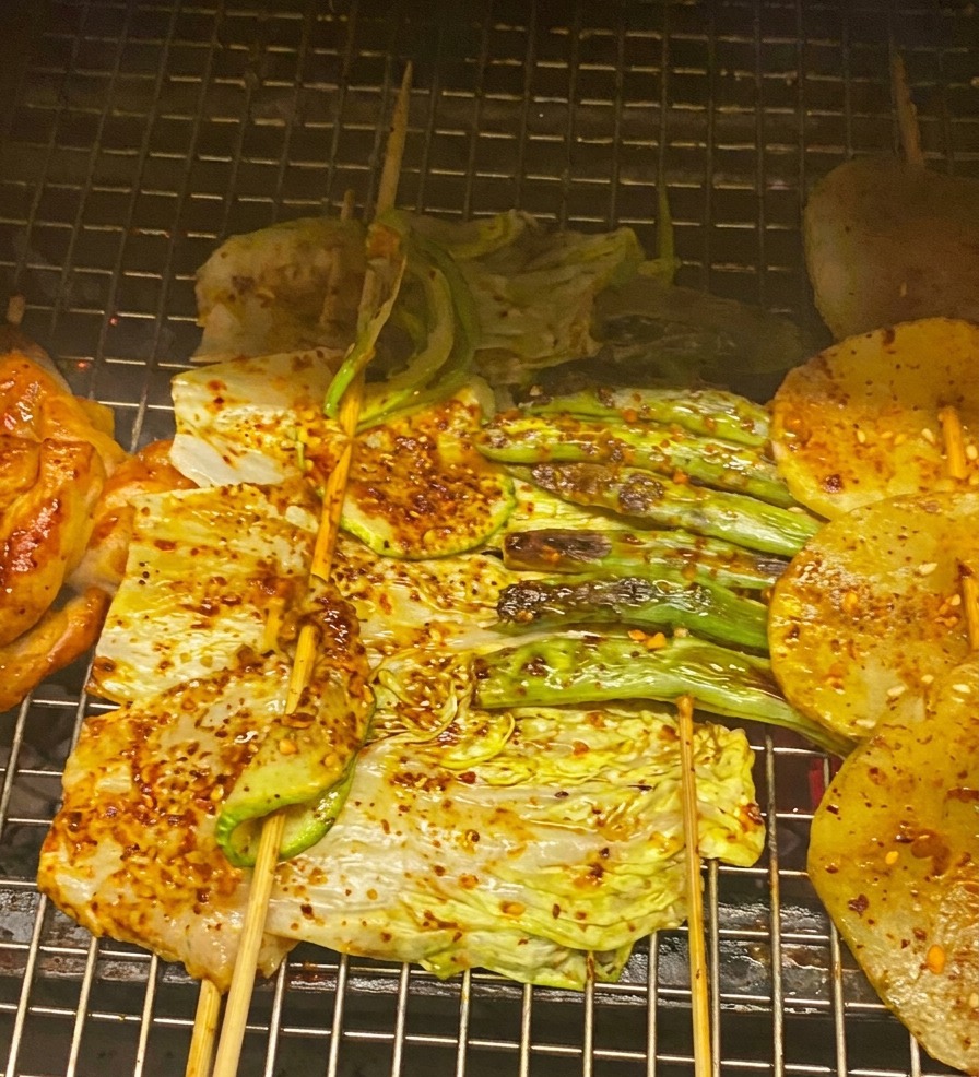 Gros plan sur du poulet, du chou et des courgettes grillés, badigeonnés dune sauce BBQ rouge et garnis doignons verts.