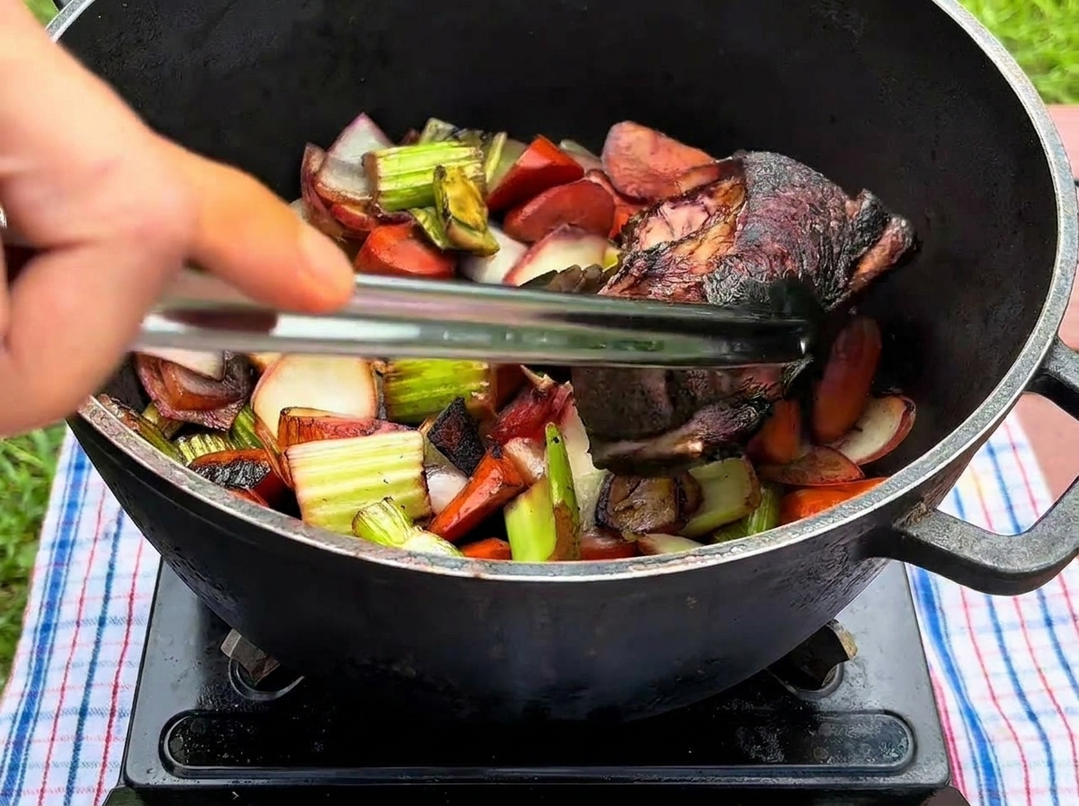 Une main utilisant des pinces pour déposer une côte de bœuf saisie dans une cocotte contenant les légumes revenus.